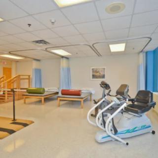 A rehabilitation room with exercise equipment and therapy beds.