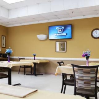 A dining area with tables, chairs, and a television on the wall.