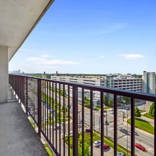 A view from a high-rise balcony overlooking an urban landscape with clear skies.