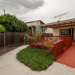 A backyard featuring a wooden deck with an adjacent small lawn and garden, enclosed by a fence.