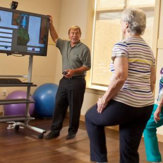 Older adults participate in a fitness class focusing on balance and physical therapy exercises.