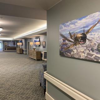 A well-lit hallway featuring a large painting of an airplane in flight.