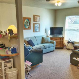 A cozy living room featuring a sofa, television, and artwork on the walls.