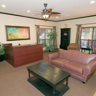 A cozy office reception area with a sofa, coffee table, desk, and artwork on the wall.