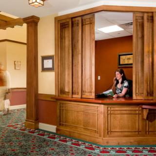 A reception area with a wooden desk and an employee speaking on the phone.