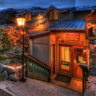 A cozy restaurant entrance illuminated by a warm glow and a street lamp at night.