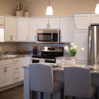 A modern kitchen with white cabinets, stainless steel appliances, and an island with seating.
