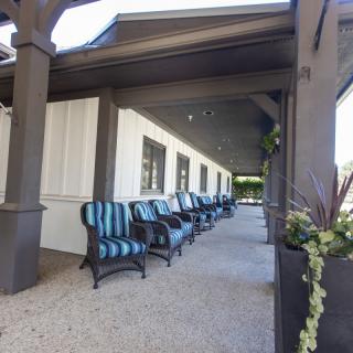 A row of striped chairs on an outdoor patio with a white building exterior.