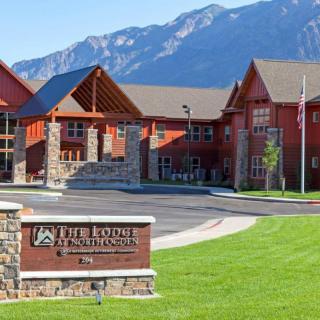 A scenic view of a modern building complex set against a backdrop of mountains, with a sign in the foreground.