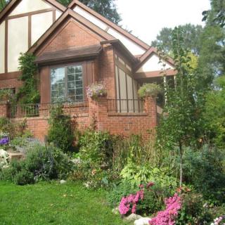 A charming brick house with a lush garden full of colorful flowers.