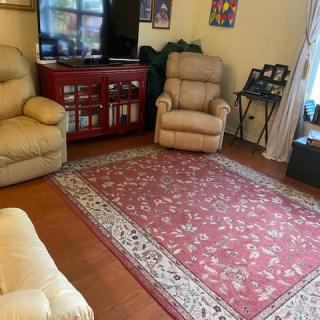 A cozy living room with beige sofas, a patterned rug, and a television.