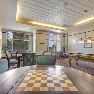 A spacious and well-lit game room featuring a chessboard and a pool table.