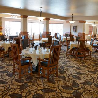 A spacious and elegantly designed dining room with neatly arranged tables and chairs on a patterned carpet.