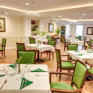 A neatly arranged dining area with tables and green chairs, set for a meal.