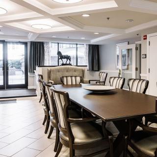 An elegant dining room with a long table and chairs, featuring ceiling lights and tasteful decor.