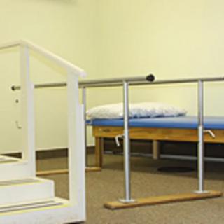 A physical therapy clinic equipped with parallel bars and a treatment table.