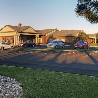 A view of a residential building with cars parked in the lot during sunset.