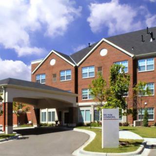 A view of a brick residential building with multiple windows and landscaped surroundings.