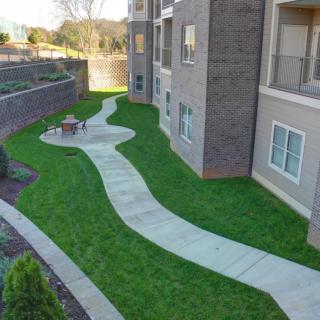 A landscaped area with a winding walkway beside an apartment building.