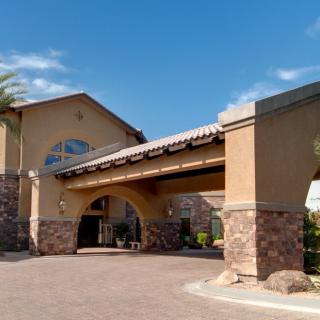 A sunny daytime view of a hotel entrance with palm trees and an archway.