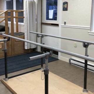 A physical therapy room featuring parallel bars used for rehabilitation exercises.
