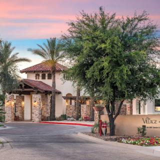 A beautiful entrance to a modern architectural residence surrounded by palm trees during sunset.