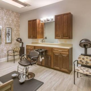 A cozy salon interior featuring a hairdressing station with a chair, mirror, and cabinetry.