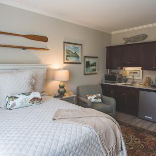 A cozy hotel room featuring a comfortable bed, tasteful decor, and a small kitchenette.