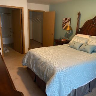 A cozy bedroom featuring a neatly made bed, warm colors, and inviting decor.