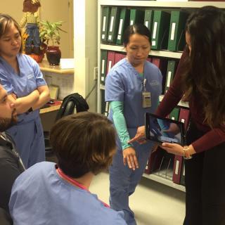 A medical team engaged in a discussion, with one member demonstrating something to the others.