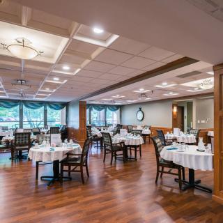 An elegant restaurant dining room with neatly arranged tables and chairs on a wooden floor.