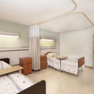 A view of a hospital patient room featuring two beds and a clean, calm environment.