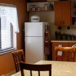 A cozy kitchen interior with a refrigerator, wooden table, and chairs.