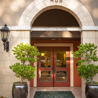 An elegant building entrance with double wooden doors and potted plants.