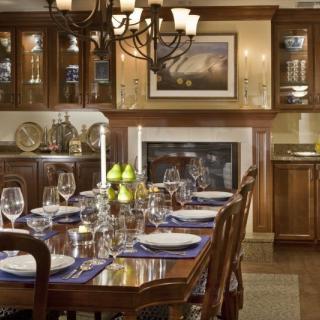 An elegantly set dining room table with a chandelier and wood furnishings.
