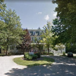A large house surrounded by trees with a winding driveway.