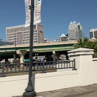 A bustling urban landscape featuring modern buildings and a highway under a clear blue sky.