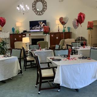 A beautifully decorated dining area ready for a Valentine's Day celebration, featuring tables set with white tablecloths and heart-shaped balloons.