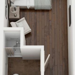 A top-down view of a compact apartment floor plan featuring a bedroom with wooden flooring and modern furnishings.