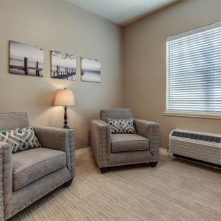 A cozy living room with two gray armchairs, a lamp, and wall art.