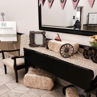 A decorated lobby with vintage elements, including hay bales and a wagon wheel, beneath a large mirror and patriotic flags.