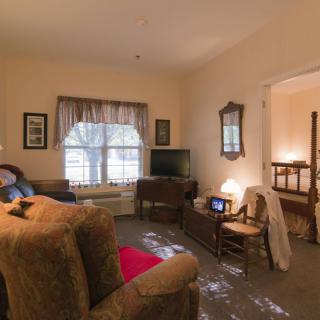 A cozy living room with a sofa, television, and window with curtains.