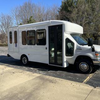 A white bus parked in a sunny outdoor parking lot.