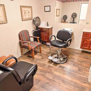 A cozy hair salon interior with styling chairs and various equipment.