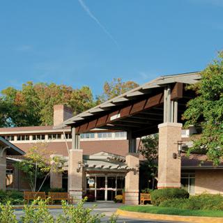 A modern building entrance surrounded by greenery under a clear blue sky.