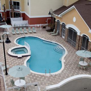 An aerial view of a resort swimming pool with surrounding lounge chairs and patio tables.