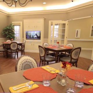 A warmly lit dining room with elegantly set tables and comfortable seating.