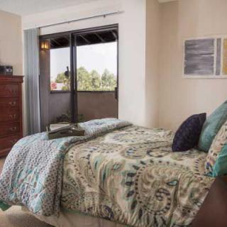 A cozy bedroom with a patterned bedspread and a view through a glass door.