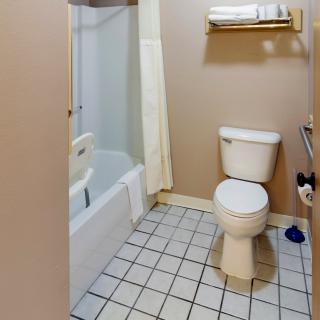 A clean and functional bathroom with a toilet, bathtub, tiled floor, and towel rack.