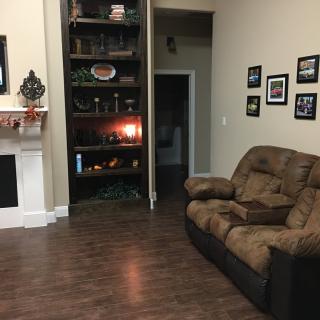 A cozy living room with a sofa, fireplace, and decorative shelving.